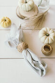 Autumnal arrangement of pumpkins and linen napkins with cane napkin rings on table