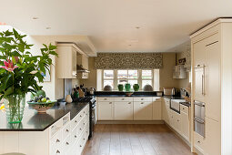 White units with black granite worktops in stylish kitchen with decorative confit jars