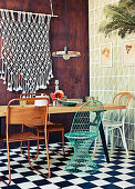 Dining table with various chairs, macrame wall hanging above