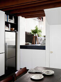 Stainless steel fridge combination in white kitchen, dining table in the foreground