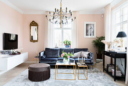 Dark velvet sofa, console table, pouffe, delicate coffee table and TV cabinet in pale pink living room