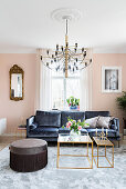 Dark velvet sofa, delicate coffee table and pouffe in pale pink living room