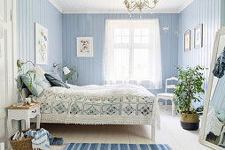 Crocheted blanket on double bed in bedroom with pale blue walls