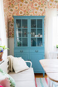 Blue dresser in dining room with floral wallpaper