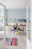 Colourful retro furniture in open-plan kitchen-dining room seen through double doors