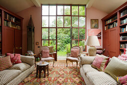 Couch, antique armchairs and bookcases in living room in shades of pink