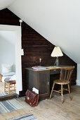 Old desk against rustic wooden wall in attic