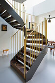 Geschwungene Treppe mit furnierten Stufen und goldenem Geländer