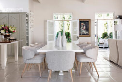 White dining table and elegant upholstered chairs in open-plan interior