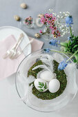 A wreath of moss with Easter eggs and spring flowers in glasses