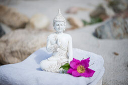 Buddha figurine and flower on towel