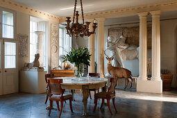 Marble topped table and regency chairs in entrance hall with centaur plaster cast and taxidermy stag