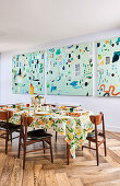 Three-part abstract mural in front of a set dining table with a Mediterranean tablecloth