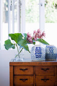 Blume in Glasvase und chinesisches Porzellan auf Kommode