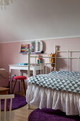 Metal bed with valance in child's bedroom with pink wall