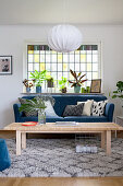 Blue sofa below lattice window with plants on sill in living room