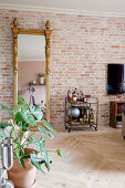 Vintage serving trolley and gilt-framed mirror against brick wall