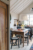 Black spoke-back chairs around wooden table in rustic kitchen-dining room