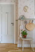 Stool below row of pegs on wall with wainscoting