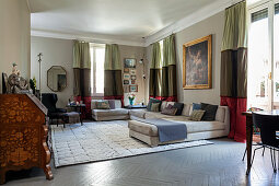 Pale sofa set and antique bureau in open-plan interior