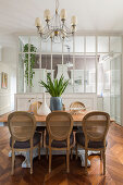 Medallion chairs around dining table in front of kitchen separated by glass wall in period building