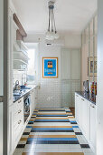 Küche mit weißen Fronten, buntem Fliesenboden und U-Bahn-Fliesen