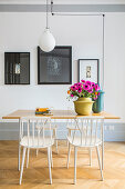 White spoke-back chairs around table with vase of pink anemones