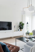 Flatscreen TV above low sideboard in white-and-grey living room