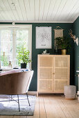 Sessel und halbhoher Schrank im Wohnzimmer mit grüner Wand