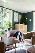 Sessel um Couchtisch und halbhoher Schrank im Wohnzimmer mit grüner Wand