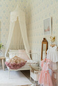 Canopied bed and pastel wallpaper in girl's bedroom