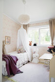 Canopied bed, large Miffy lamp and pastel wallpaper in girl's bedroom