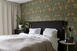Double bed against wall with William Morris wallpaper