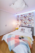 Butterfly wallpaper behind bed in bedroom with fitted wardrobes