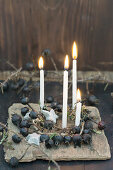 Kranz aus schwarzen Hagebutten mit vier Kerzen und Sternen aus Birkenrinde