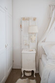 Lamp mounted on old window shutters on wall above vintage-style bedside table
