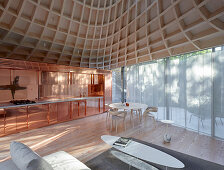 Offener Wohnraum mit Lounge, Küche in Kupfer, Glasfront und trichterförmigem Dach