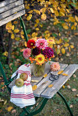 Autumn bouquet of dahlias and rose hips on a chair
