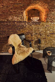 Coffeetable und schwarzer Designerstuhl mit Schaffell in restauriertem Gewölbekeller