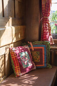 Colourful scatter cushions on bench in sunny farmhouse parlour