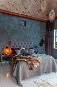 Elegant, rustic bedroom with mottled painted wall and ornately painted ceiling