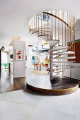 Wendeltreppe mit messingfarbenem Geländer in offenem Wohnraum einer Designerwohnung