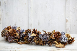 Winter arrangement of leaves and pine cones dipped in coloured wax or sprayed gold
