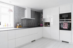 Schlichte weiße Küche mit grauen Arbeitsplatten und grauer Rückwand