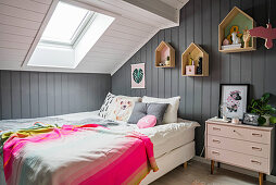 Schlafzimmer unter Dachschräge mit dekorativen Wandregalen in Häuschenform
