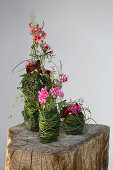 Summer flowers in various vases decoratively wrapped in leaves and grasses