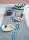 Tablecloth runner printed with leafy tendril on simply set table