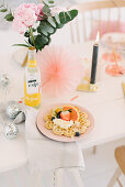 Waffle and fruit on table festively decorated with glittery balls, candle and paper rosettes