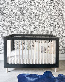 Crib, rabbit wallpaper and blue cowhide rug in nursery