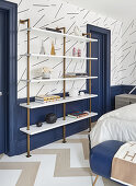 White shelving with brass frame against blue wainscoting in bedroom